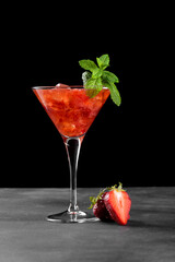 Cold summer strawberry cocktail mojito, margarita, daiquiri in a martini glasse. Fresh strawberry drink with ice cubes and mint leaves on dark background. Iced strawberry lemonade