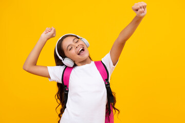 Amazed child singing. Amazed teen girl. School teenager child girl in headphones with school backpack. Teenager student, isolated background. Learning music. Excited expression, school leisure. - obrazy, fototapety, plakaty