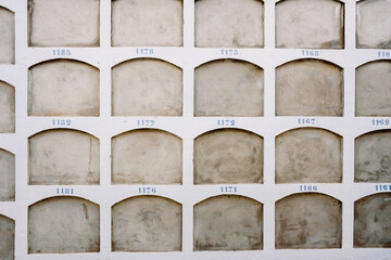 Wall of a cemetery with the holes of the niches one on top of the other covered. - obrazy, fototapety, plakaty