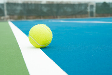 Tennis ball near the doubles side line on a court.