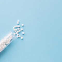 Homeopathic pills and plastic container on a blue background. Homeopathic medicine