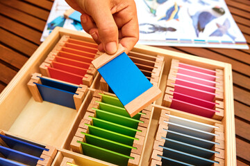 Girl holds a tablet from a montessori color box, gradient colors to match the visual sense.