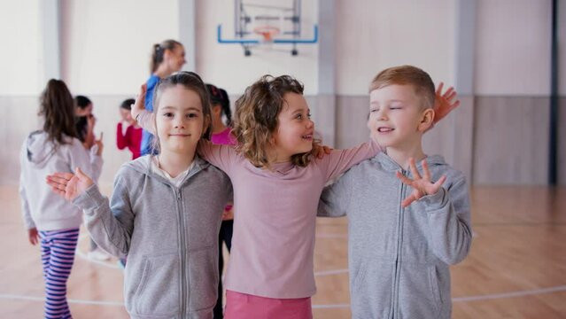 Group Of Happy Pupils Looking At Cmaera Indoors In Gym During PE Class