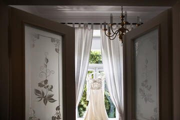 Wedding dress hanging on the window in the room