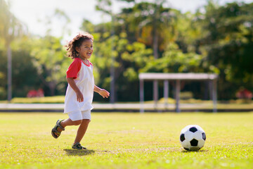 Cute curly little boy playing football. Kids play.