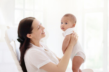 Mother and baby in white bedroom. Asian mom.