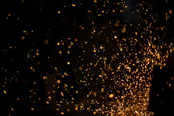 Lots of sparks from cutting metal in dark. Lights fly in different directions. Industrial background.