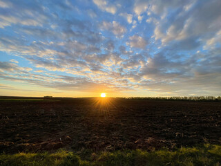 Dramatic sunset sky with clouds. Spectacular sunset over the field