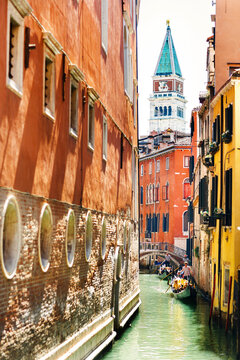 View of the San Marco tower and and the gondola between the colored houses