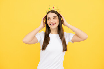 Fototapeta na wymiar Portrait of arrogance woman with golden crown on head, leadership and success. Attractive rich arrogant girl wearing crown isolated over yellow background.
