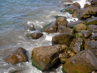Surf. Waves crash on big rocks. Rocky coast and wave.