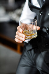 Groom in suit with whiskey glass at wedding