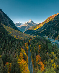 High angle aerial view of river and road running through forest and mountainous landscape