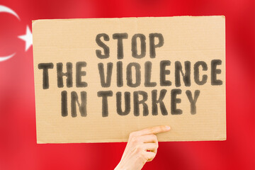 The phrase " Stop the violence in Turkey " is on a banner in men's hands with a blurred Turkish flag in the background. Sad. Rights. Security. Social. Stress. Combat. Hate. Cruelty. Furious