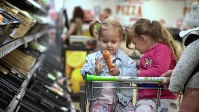 Shopping list food crises concepts. Father with Two daughters at Supermarket. Children sitting in cart. Kids Siblings with Dad buy fresh vegetables and fruits. Healthy eating Lifestyle. Fatherhood