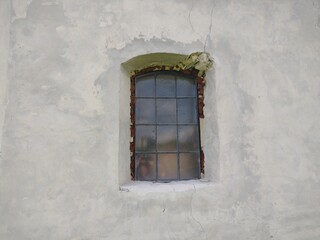An old window in the gray wall of an church.