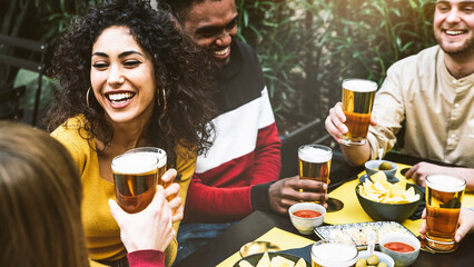 Multi-ethnic friends enjoying happy hour drinking beer at brewery pub - Group of young people...