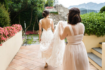 Bridesmaid helps the bride to hold the dress