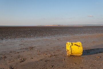 A yellow plastic bucket litters the beach at Instow, Devon