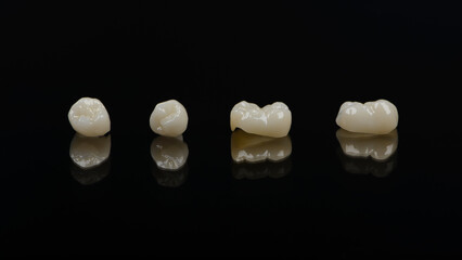 Qualified anatomic ceramic and zirconia crowns of human teeth close up macro isolated on black...
