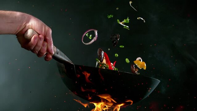 Super slow motion of flying salmon meat with asian vegetable from pan. Filmed on high speed cinema camera, 1000 fps. Speed ramp effect.