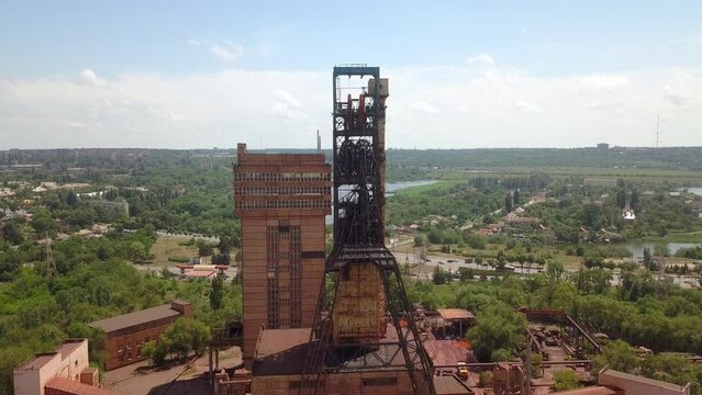 Industrial mining mine red iron ore headframe aerial drone takeoff up camera movement sunset Krivoy Rog Ukraine.