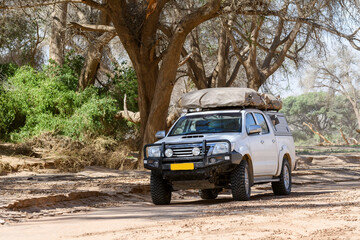 Obraz na płótnie Canvas Offroad 4X4 car with tent in African bush during a safari adventure. Camping with a rooftop tent.