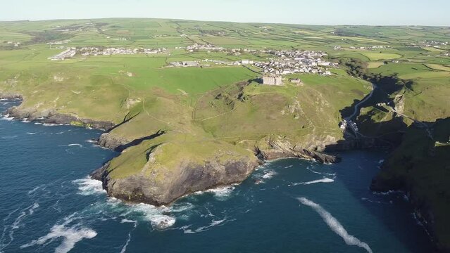 Aerial drone shot of Tintagel, rugged and rocky stretch of coastline with cliffs and rough seas, Cornwall, South West England