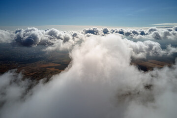 Aerial view from airplane window at high altitude of earth covered with white puffy cumulus clouds