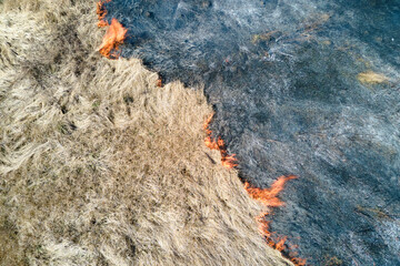 Aerial view of grassland field burning with red fire during dry season. Natural disaster and climate change concept