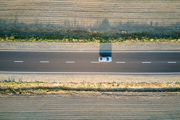 Aerial view of intercity road with blurred fast driving environment friendly electric car at sunset. Top view from drone of highway traffic in evening