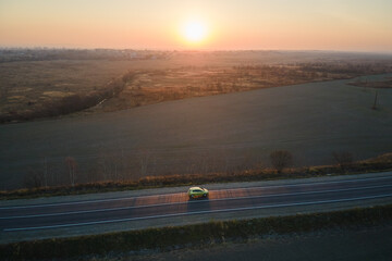Aerial view of intercity road with blurred fast driving environment friendly electric car at sunset. Top view from drone of highway traffic in evening