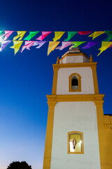 igreja sob céu em degradê no crepúsculo com bandeirinhas coloridas - obrazy, fototapety, plakaty