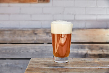 A pint of beer on a wooden bench on a patio