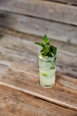 Mojito cocktail with a mint garnish on a wooden bench