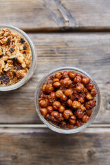 Top view of roasted chickpeas and gronola in jars on a wooden picnic table