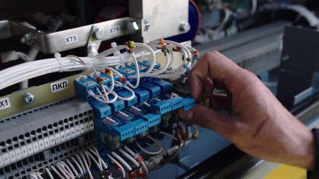 The work of an electrician close-up, an electrician of low-current equipment installs a power circuit in the circuit of electrical equipment on an electrical busbar installs an automatic interrupter