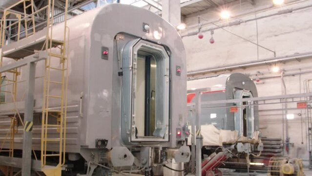Assembly shop of the wagon plant. There are two passenger cars on the assembly line, waiting for full readiness to enter the route. Cars in the depot after painting. Camera zoom in on the wagon