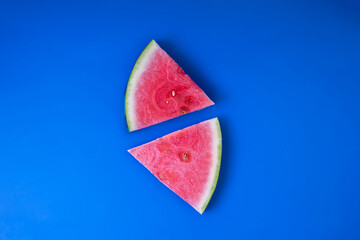 Juicy watermelon sliced into triangles. Top view of  fresh watermelon snaks lying on a blue background.
