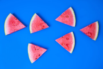 Juicy watermelon sliced into triangles. Top view of  fresh watermelon snaks lying on a blue background.
