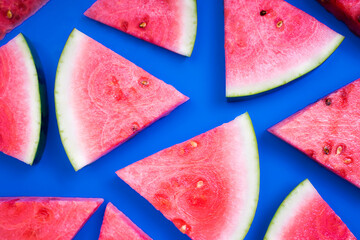 Juicy watermelon sliced into triangles. Top view of  fresh watermelon snaks lying on a blue background.
