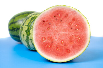 Fresh watermelon cut in half. 
Watermelons with green skin colour and red flesh inside on a white background.