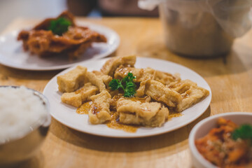 Fried tofu topping with japanese sauce on white plate with dinner meal background