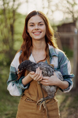 A happy young woman smiling and holding a young chicken that lays eggs for her farm