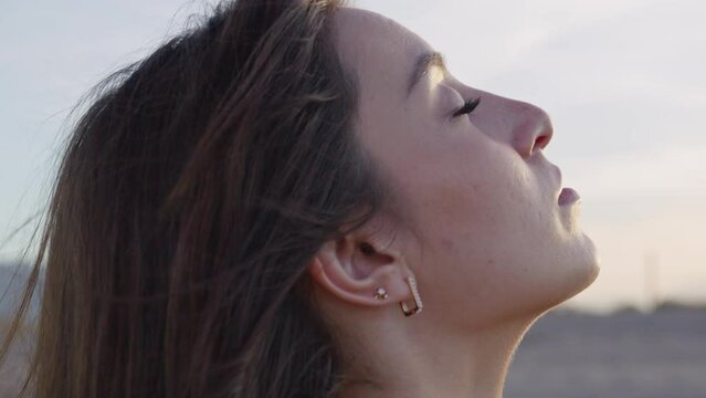 Close up side profile young white skin woman breathing and relaxed during sunset or sunrise