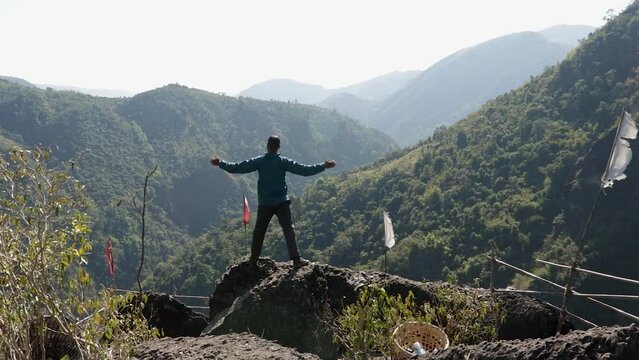isolated young man at mountain top with green forests and misty blue sky at morning from flat angle