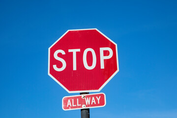 Stop sign under blue sky in USA with all way addition