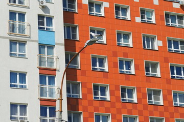Fototapeta na wymiar Modern high-rise building in a residential complex. Many windows. A seagull sits on a lamppost.