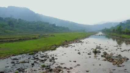 river leading to the misty mountain with cloudy sky at morning from flat angle