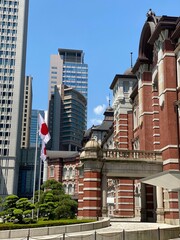 The Japanese country flag outside of the Tokyo Station building, red brick architecture on sunny weekend year 2022 June 4th